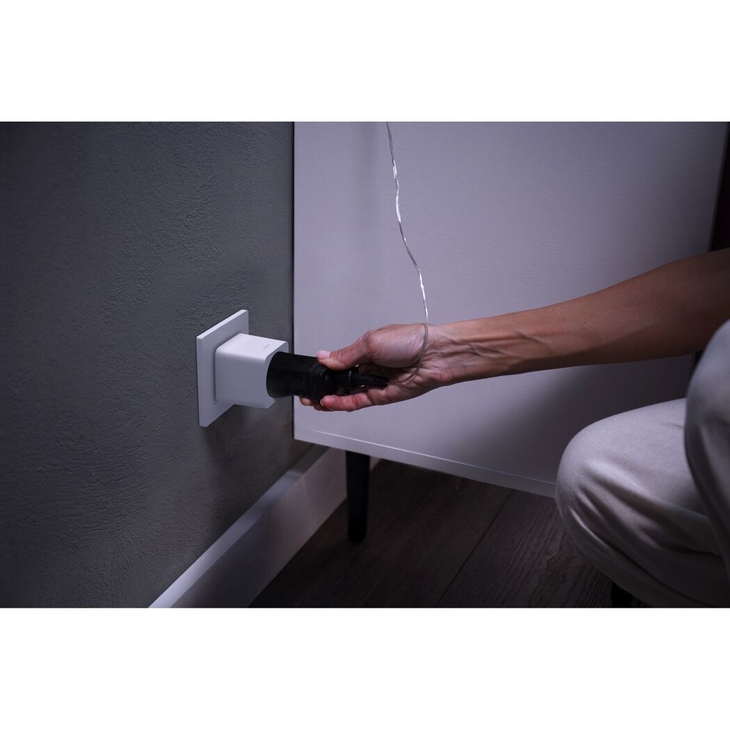 Person steckt Stecker in smarte Steckdose