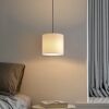 Weiße Hängelampe leuchtet über einem Nachttisch.