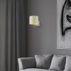 Beige Wandleuchte mit rundem Lampenschirm an grauer Wand.