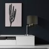 Graue Tischleuchte mit Stoffschirm auf weißem Sideboard.