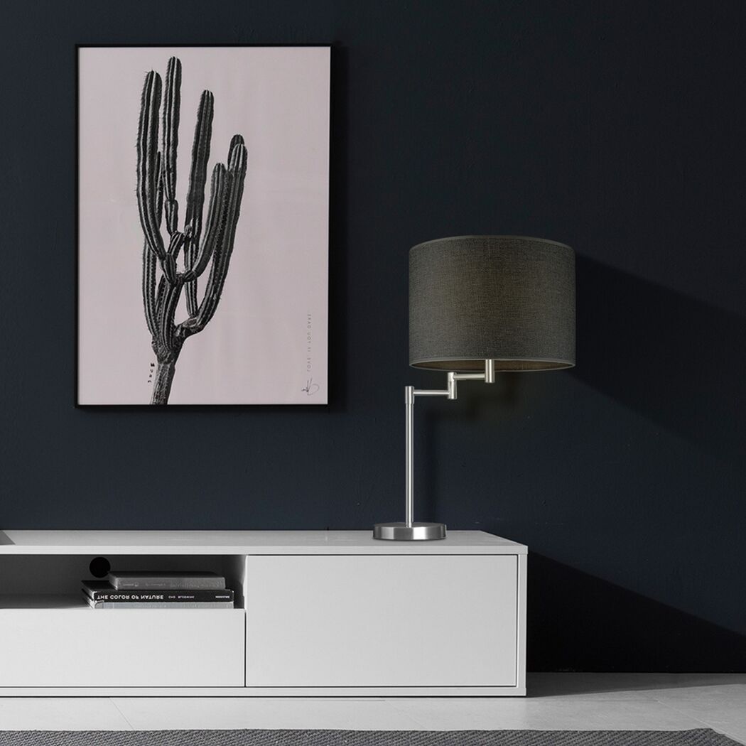 Graue Tischleuchte mit Stoffschirm auf weißem Sideboard.