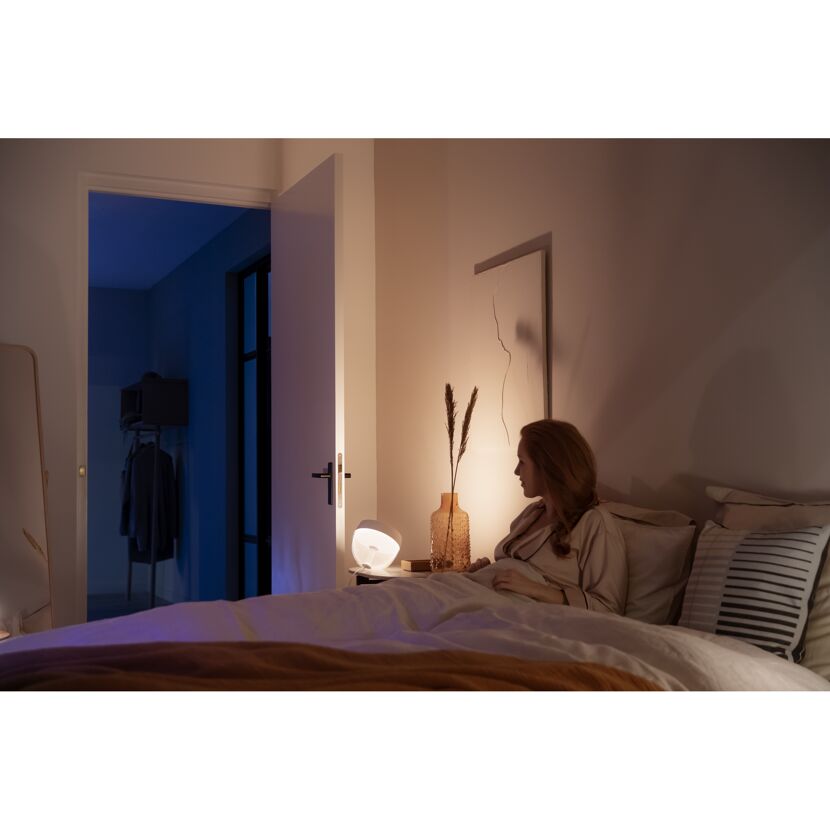 Person im Bett mit Philips Hue Iris Tischleuchte