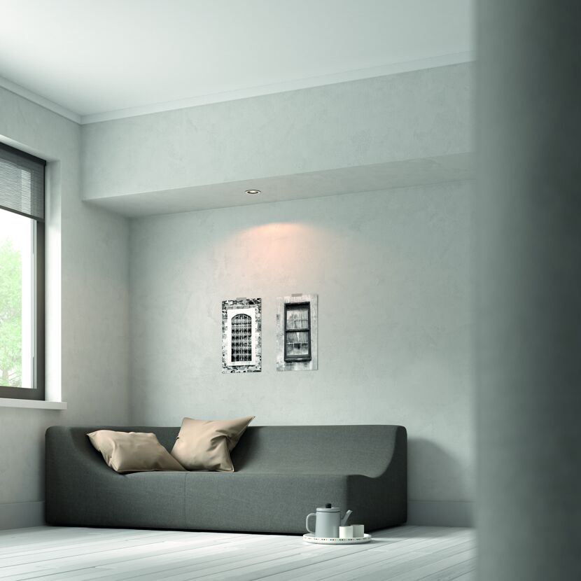 Gemütliches Wohnzimmer mit grauer Couch, Bildern und Teekanne