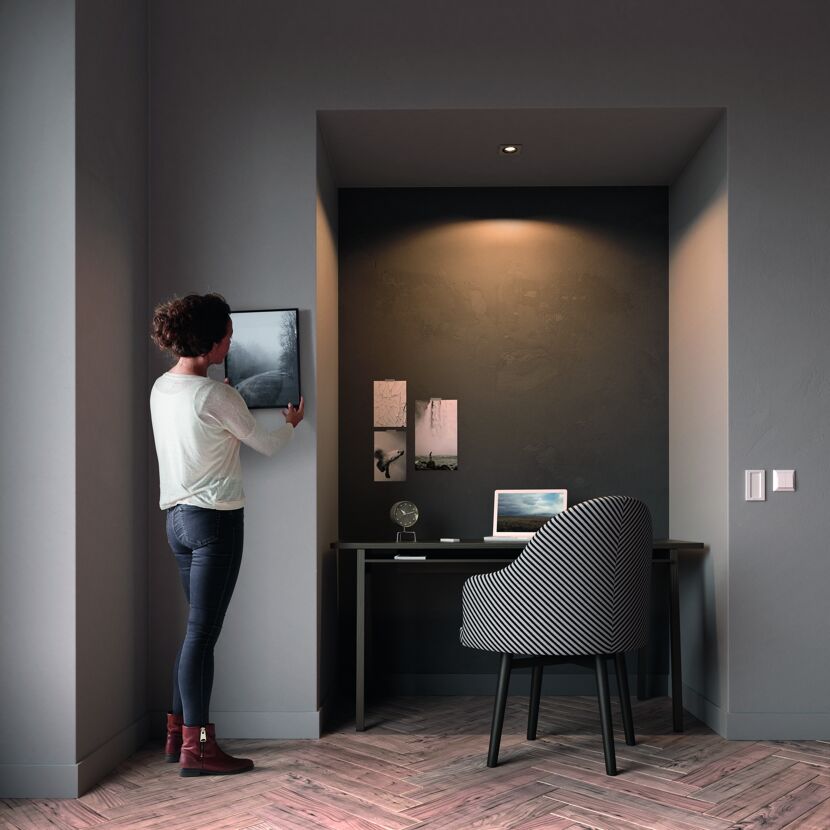 Person hängt Bild an die Wand. HUE Milliskin Espot alu, eckig