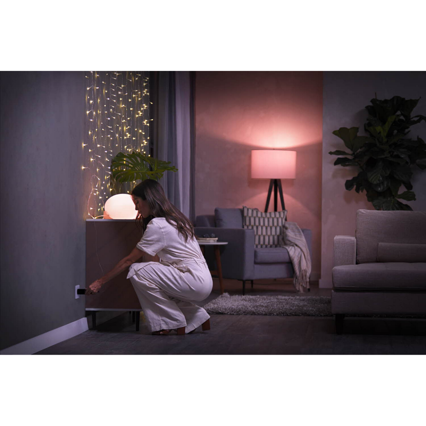 Person schliesst Lichterkette an Hue Smart Plug an