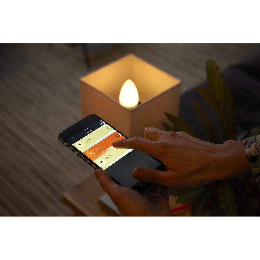 Person steuert eine Philips Hue E14 White Ambiance Lampe über eine Smartphone-App.
