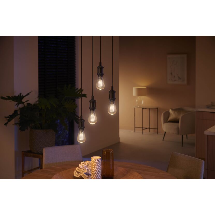 Vier HUE Filament Lampen ST64 beleuchten einen Esstisch.