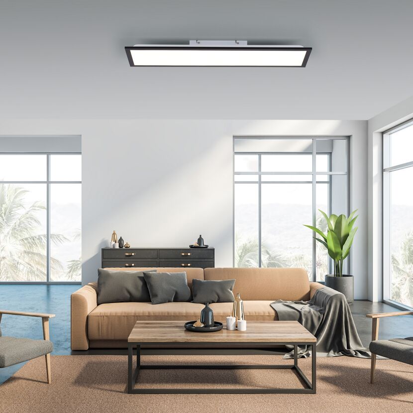 Wohnzimmer mit beiger Couch, braunem Teppich und Lampe