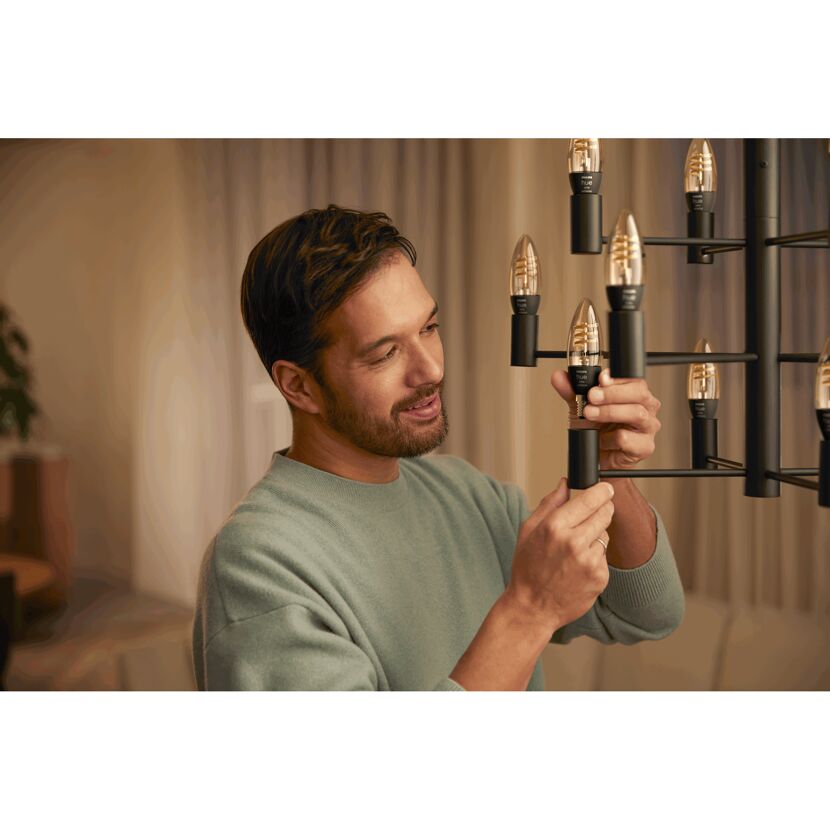 Person schraubt eine Philips Hue Kerze in einen Kronleuchter