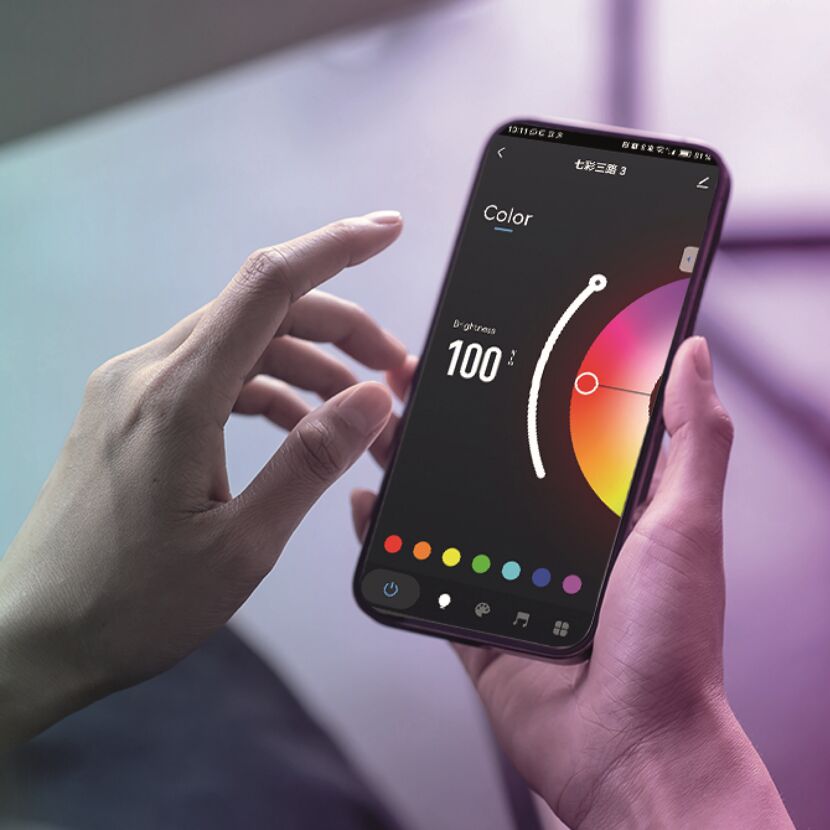 Person steuert die Farbe eines LED-Streifens über eine Smartphone-App.