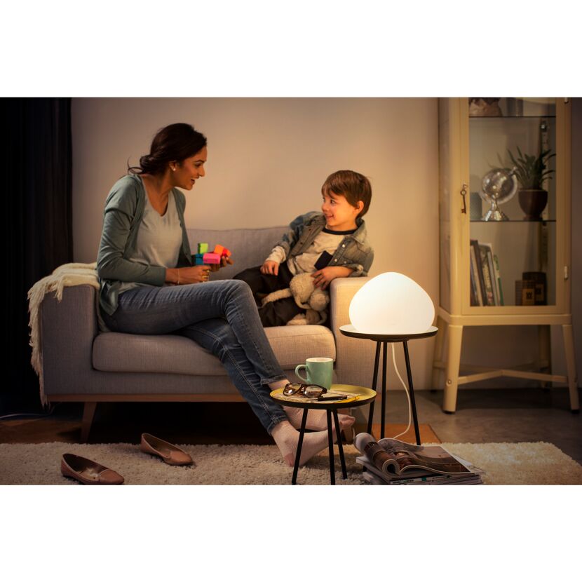 Person und Kind sitzen auf Sofa mit Tischleuchte