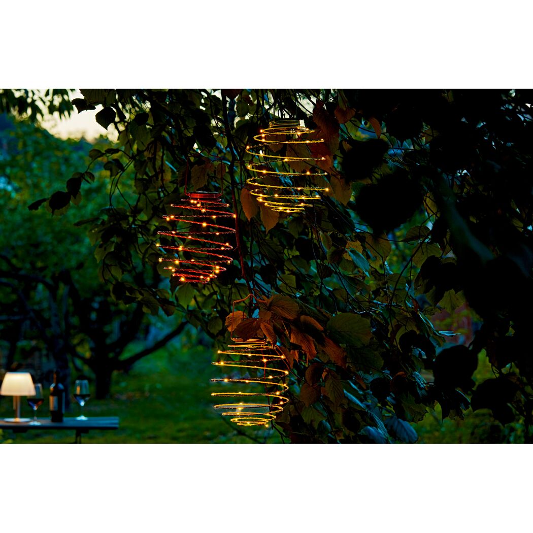 Drei Solarlampions in Spiralform hängen von einem Baum