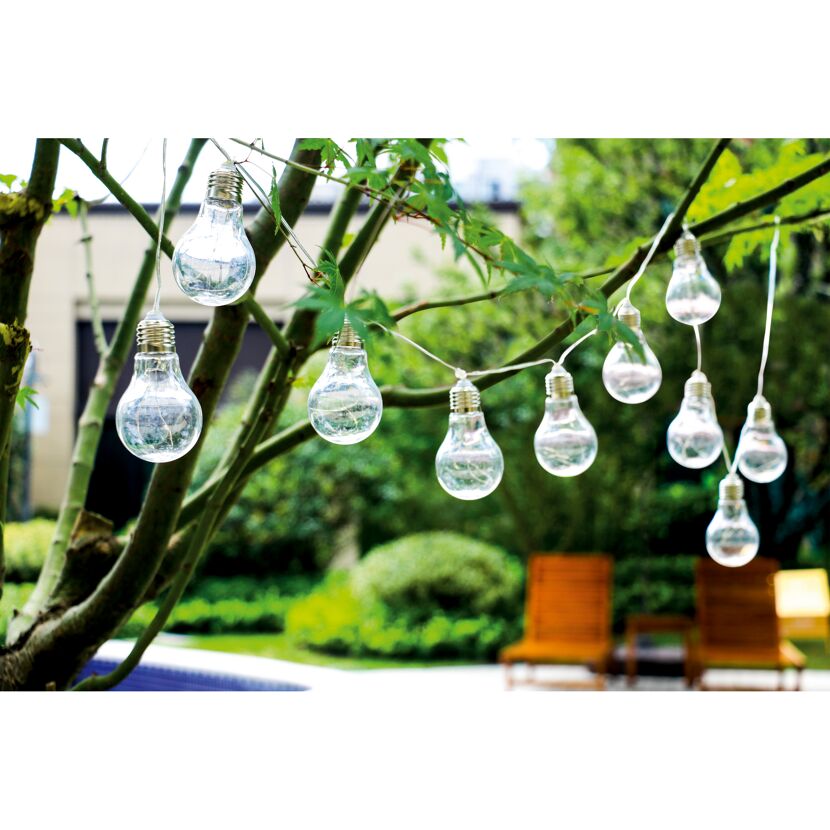 Lichterkette mit Glühbirnen hängt im Garten