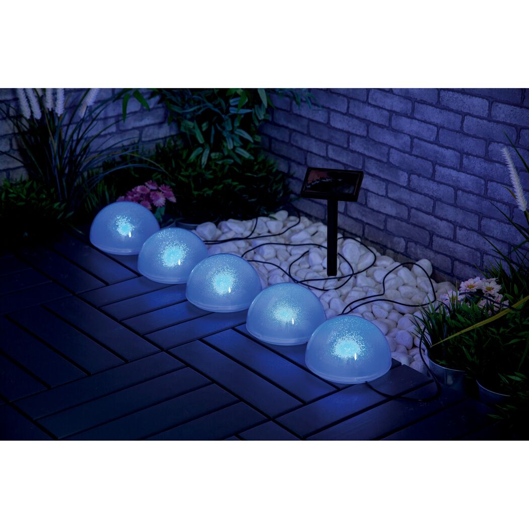 Fünf blaue Solar-Glitzerkugeln leuchten auf einer Terrasse.