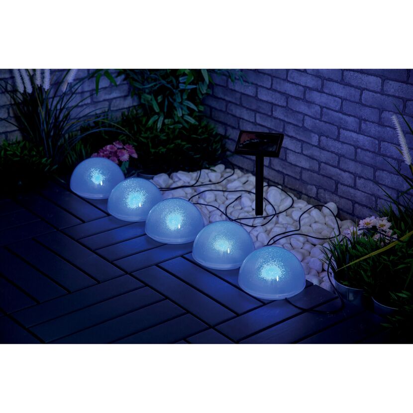Fünf blaue Solar-Glitzerkugeln leuchten auf einer Terrasse.