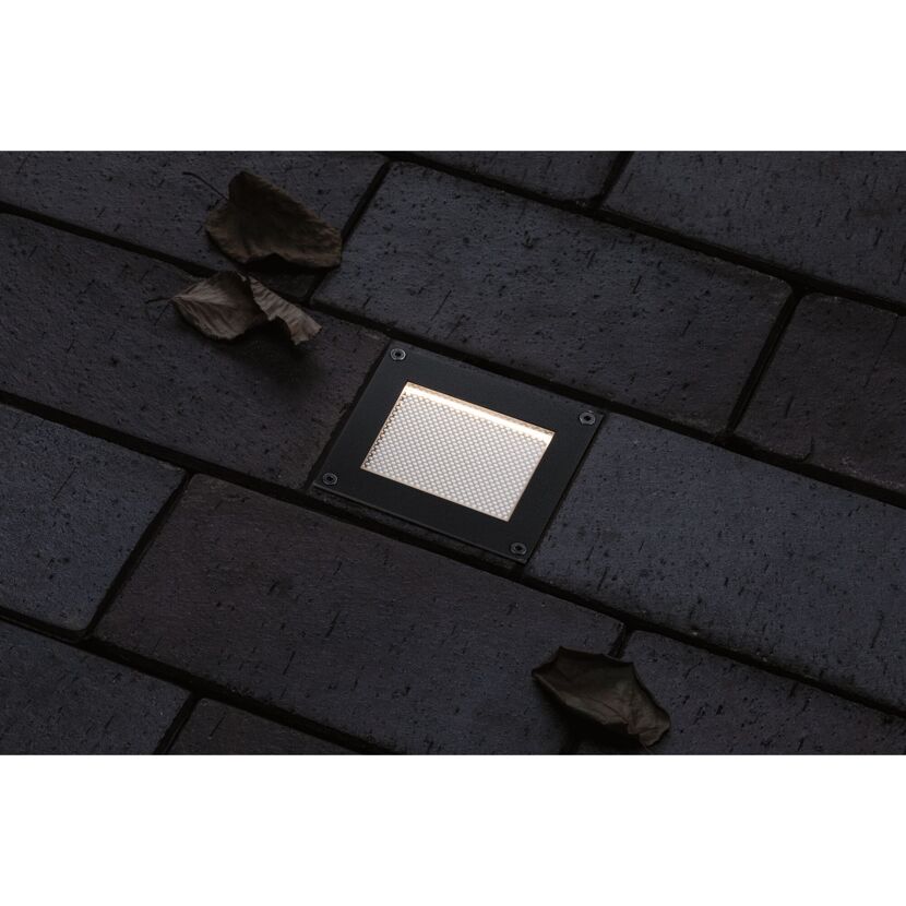 Solar Bodenleuchte auf dunklem Pflasterstein mit Blättern