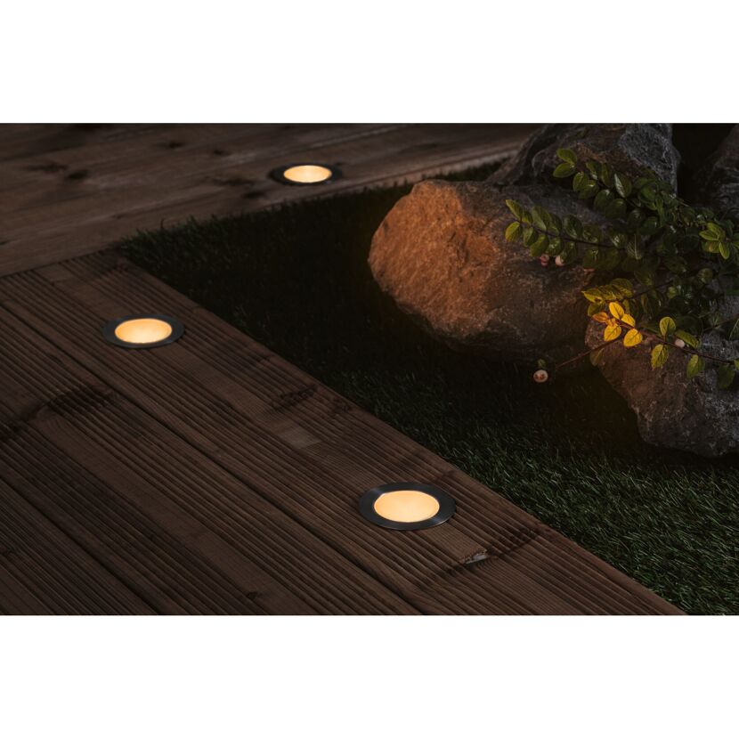 Drei leuchtende Plug & Shine Floor Spotleuchten im Garten