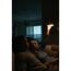 Zwei Personen sitzen auf einem Sofa und eine Person schaltet eine Lampe ein.