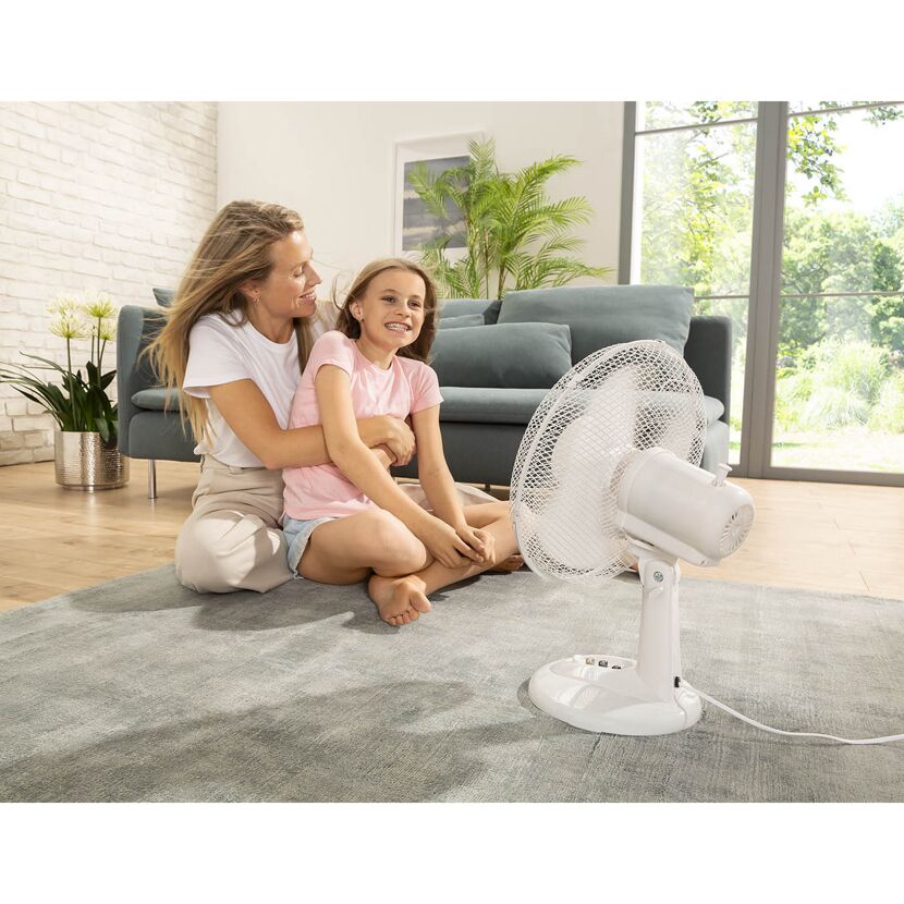 Mutter und Kind sitzen vor einem Ventilator.