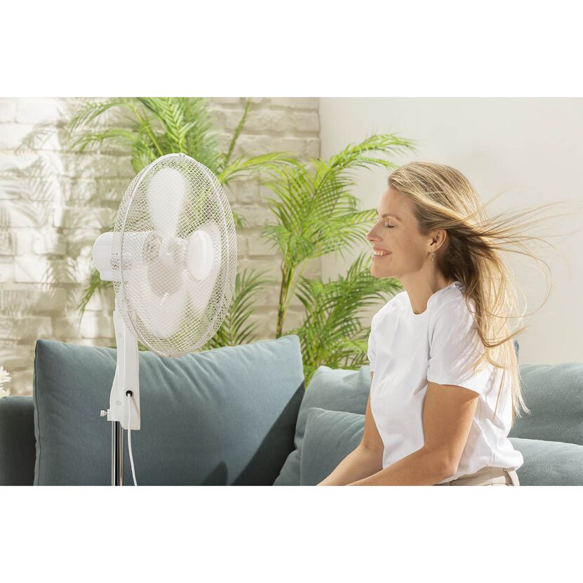 Person genießt die kühle Brise eines Standventilators.