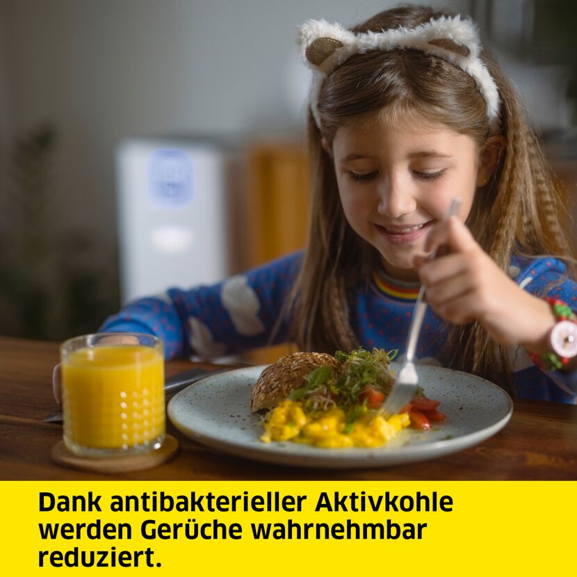 Kind isst Rührei mit Brot und trinkt Orangensaft.