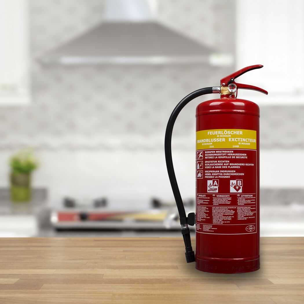 Roter Feuerlöscher auf einem Holztisch in einer Küche.