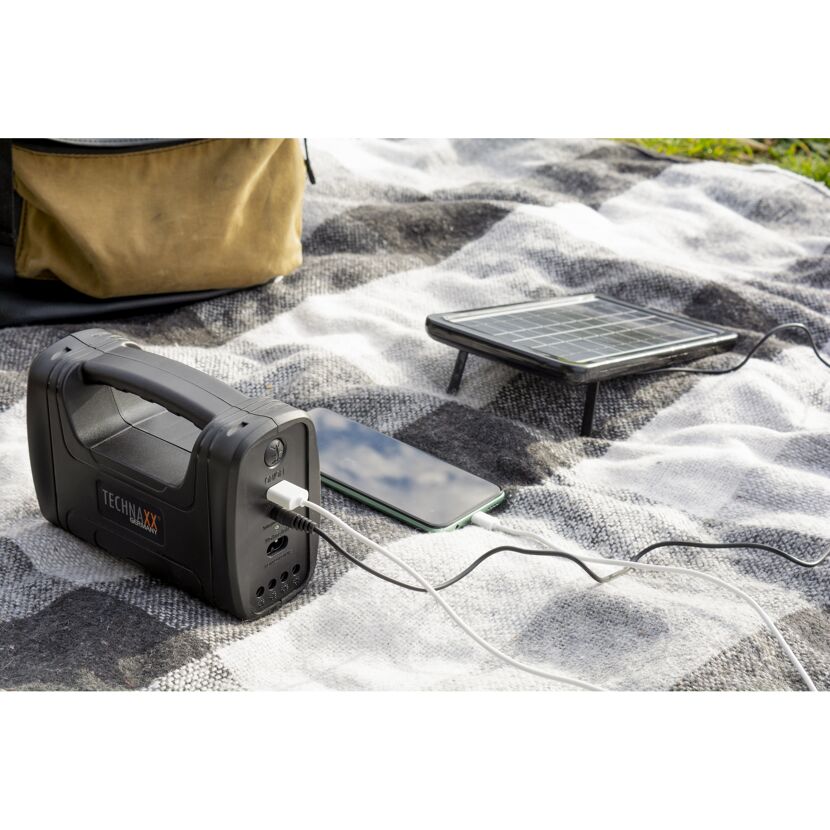 Solarpanel lädt Powerbank, die ein Handy lädt.