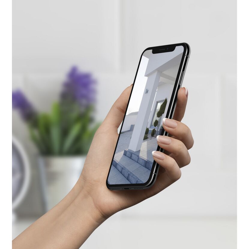 Person hält Smartphone mit Hausansicht in der Hand