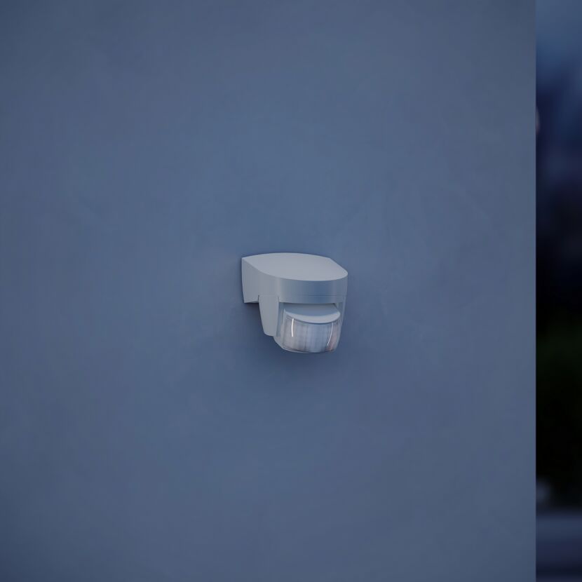 Weißer Bewegungsmelder an blauer Wand.