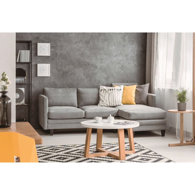 Wohnzimmer mit grauer Couch, beigen Kissen und rundem Couchtisch