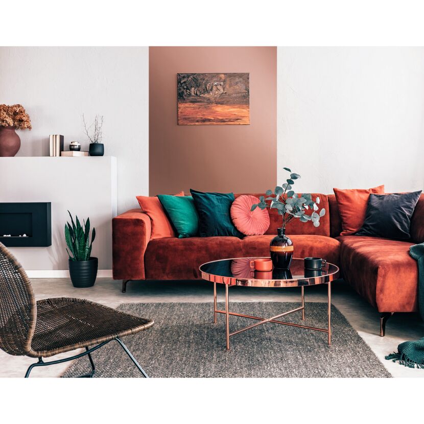 Gemütliches Wohnzimmer mit rotem Sofa, Pflanzen und Deko.