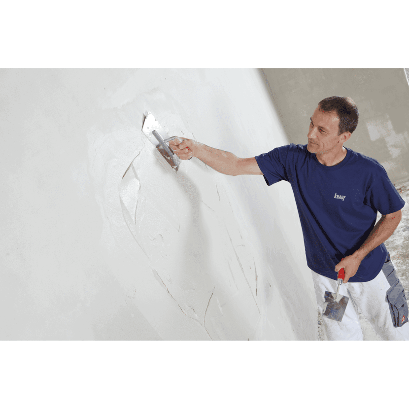 Person verputzt eine Wand mit einer Kelle.