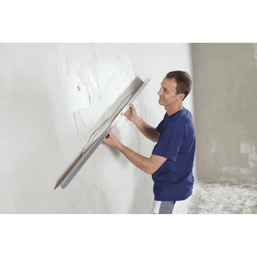 Person verputzt eine Wand mit einer Glättkelle.