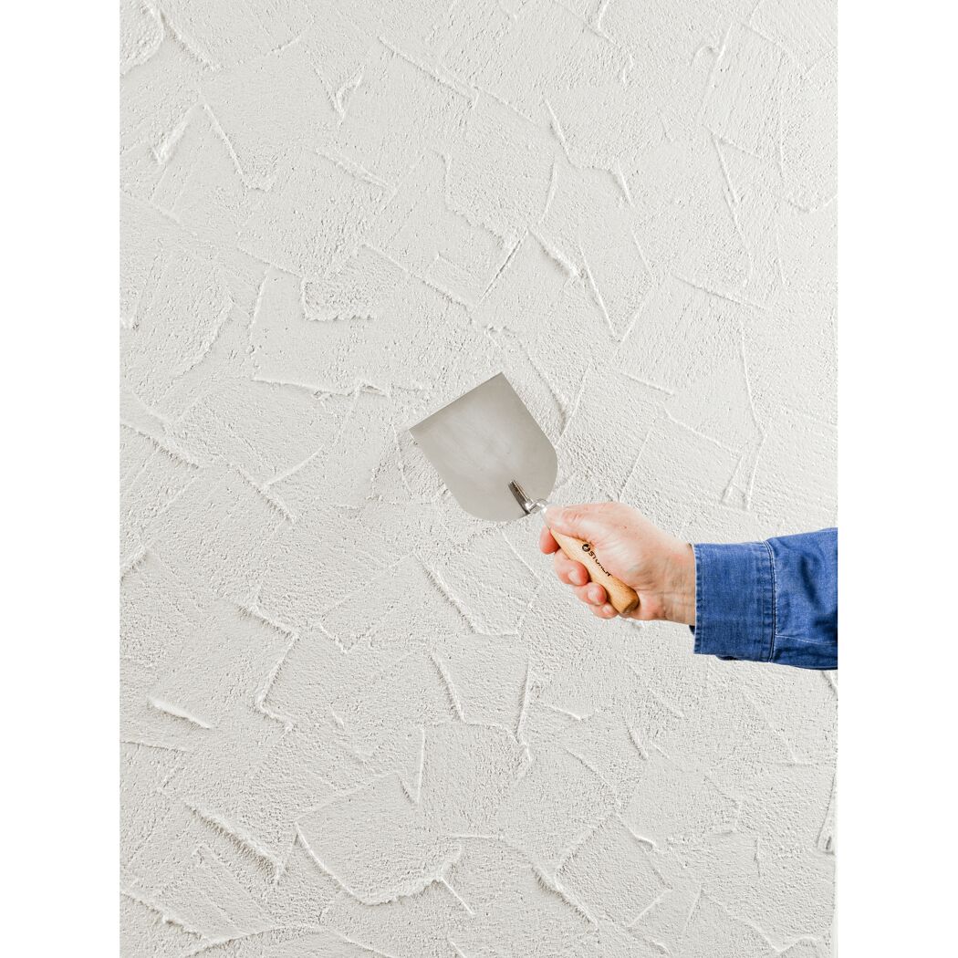 Person verputzt eine weiße Wand mit einer Kelle.