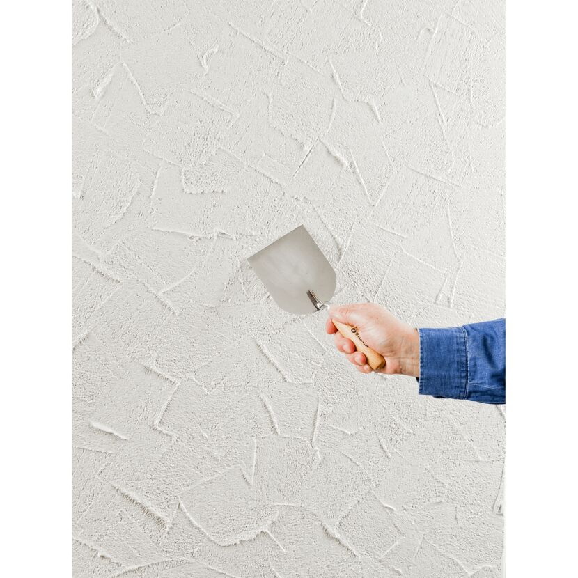 Person verputzt eine weiße Wand mit einer Kelle.