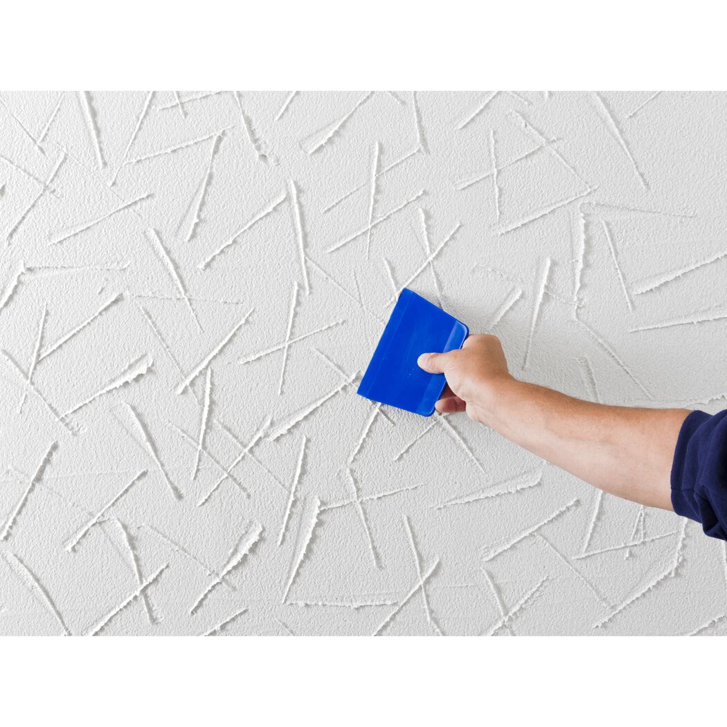 Person verputzt eine Wand mit einem blauen Spachtel.