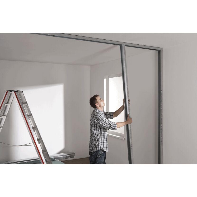 Person montiert eine Metallschiene an einer Wand.