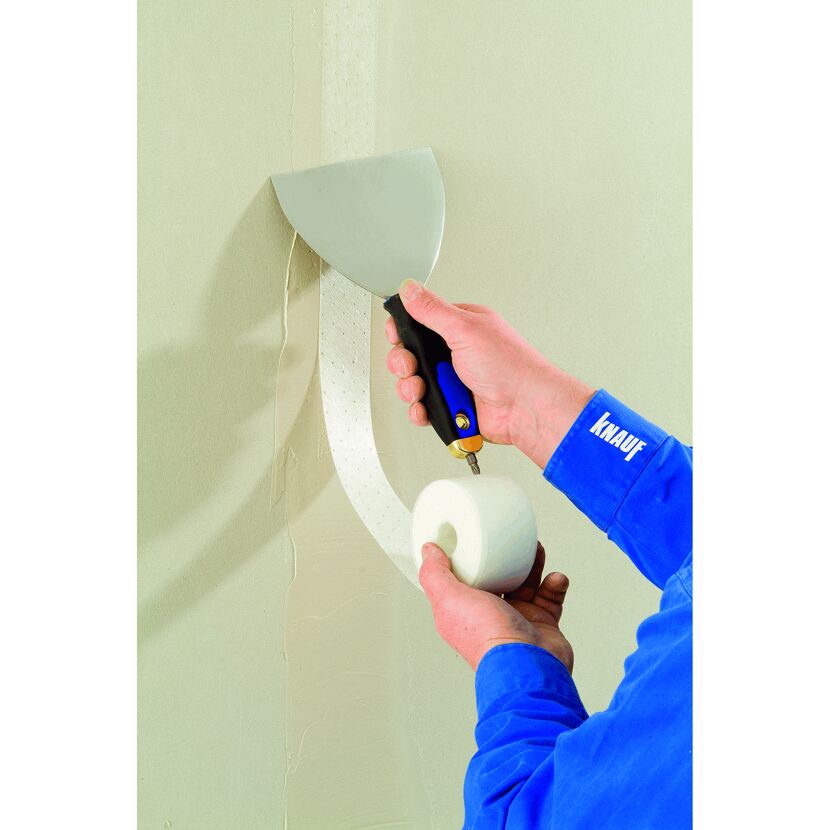 Person verwendet Spachtel und Fugenband an Wand