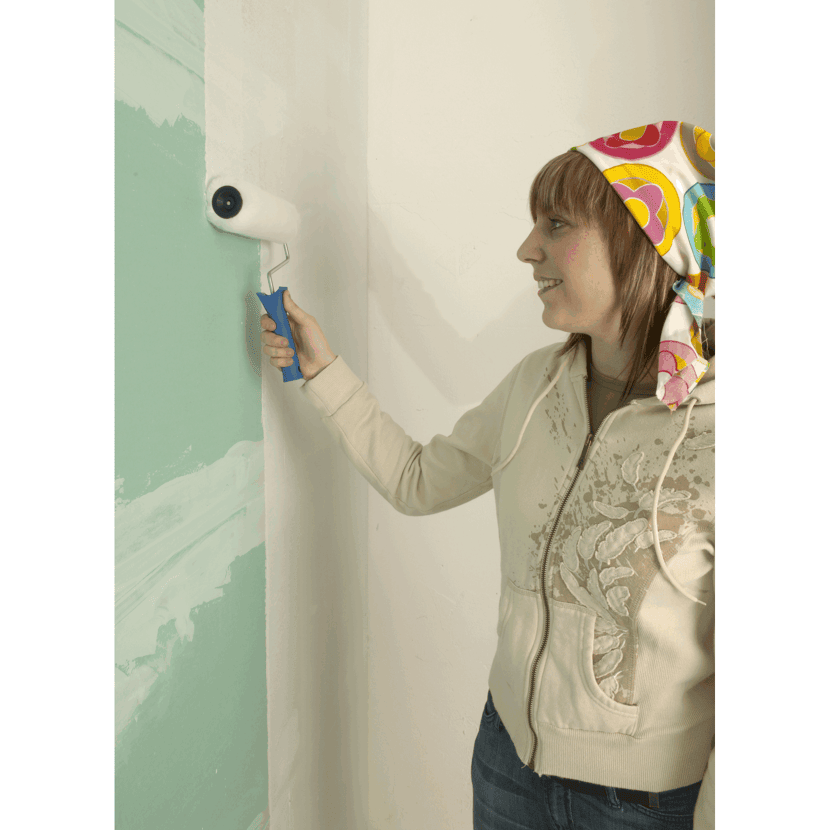 Person streicht eine Wand weiß mit einer Farbrolle.