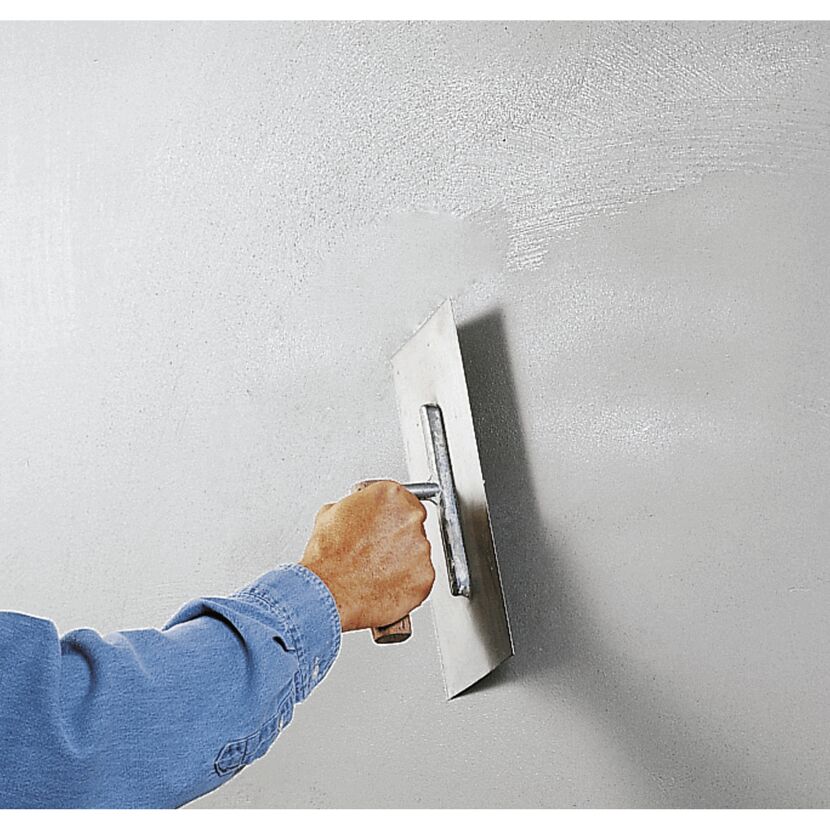 Person verputzt eine Wand mit einem Flächenglätter.